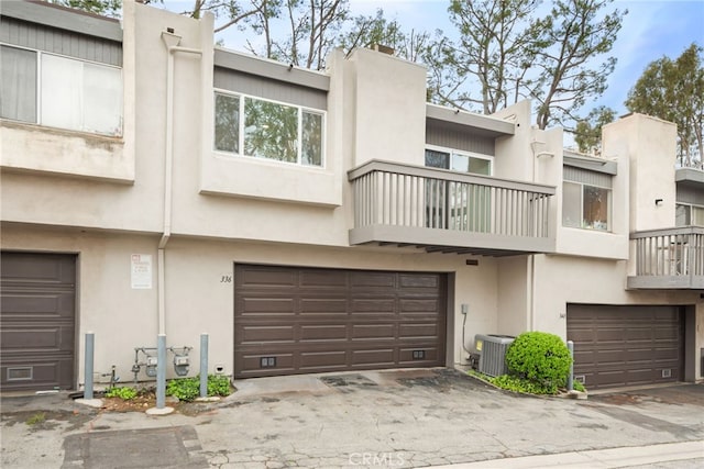 townhome / multi-family property featuring a chimney, cooling unit, a garage, and stucco siding