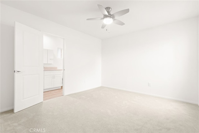 spare room featuring baseboards, light colored carpet, and ceiling fan
