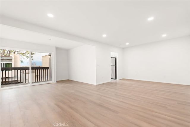 spare room with baseboards, recessed lighting, and light wood finished floors