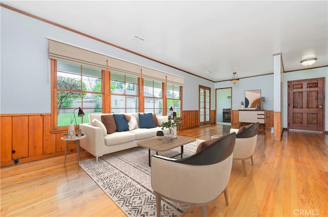living area featuring a wainscoted wall, light wood-style flooring, and crown molding