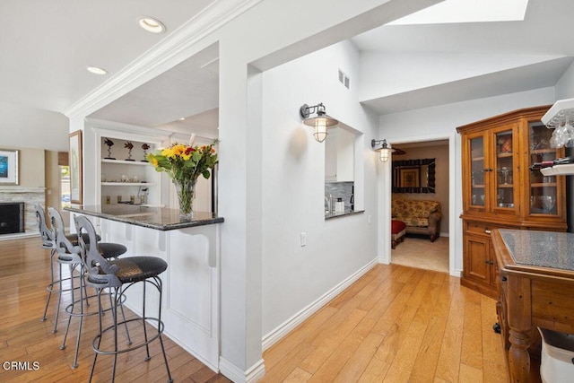 2231 Peninsula Rd, Oxnard, CA 93035 - kitchen with vaulted ceiling, a kitchen breakfast bar, light wood-type flooring, visible vents, and ornamental molding