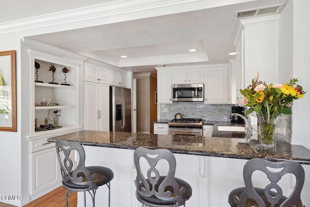 2231 Peninsula Rd, Oxnard, CA 93035 - kitchen featuring a tray ceiling, a sink, visible vents, a peninsula, and appliances with stainless steel finishes