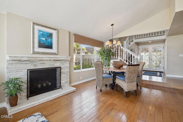 2231 Peninsula Rd, Oxnard, CA 93035 - dining room with a chandelier, hardwood / wood-style floors, vaulted ceiling, french doors, and a stone fireplace