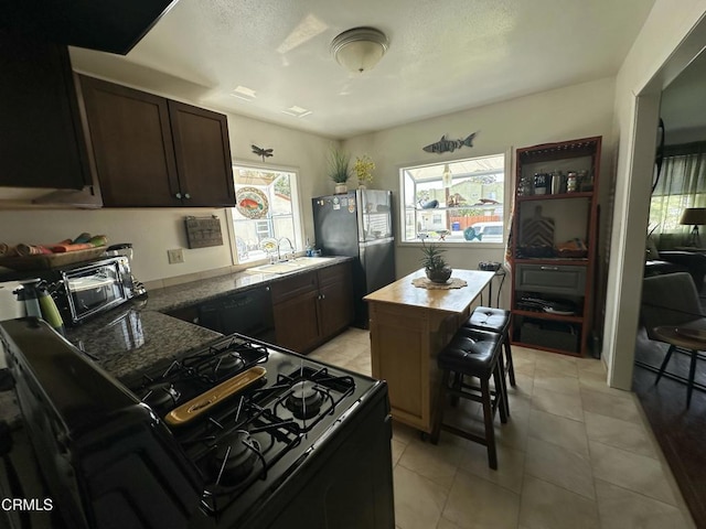 kitchen with dark brown cabinets, light tile patterned flooring, a sink, and black appliances