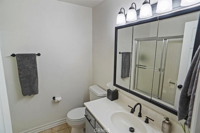 bathroom with toilet, tile patterned flooring, a shower with shower door, vanity, and baseboards