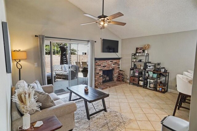 living room with ceiling fan, light tile patterned floors, high vaulted ceiling, a fireplace, and baseboards