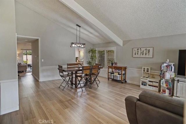 dining room with a textured ceiling, lofted ceiling, light wood-style flooring, and a chandelier