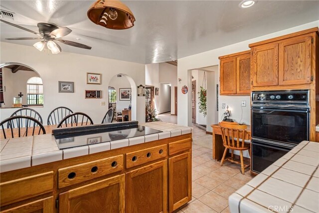 5420 Clayvale St, Acton, CA 93510 - kitchen with tile counters, black appliances, arched walkways, ceiling fan, and light tile patterned flooring
