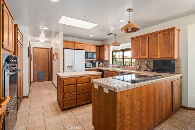5420 Clayvale St, Acton, CA 93510 - kitchen featuring black appliances, a skylight, light tile patterned flooring, tile counters, and backsplash