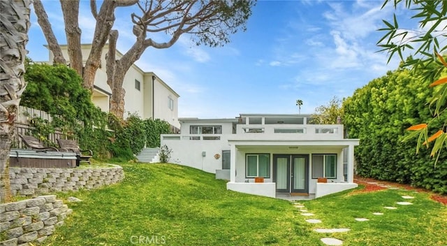 back of property with french doors, a yard, and stucco siding