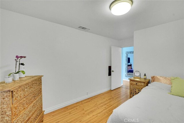 bedroom featuring baseboards, visible vents, and light wood-style floors