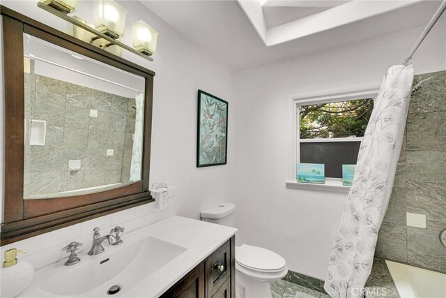 bathroom with marble finish floor, toilet, vanity, decorative backsplash, and shower / bath combo