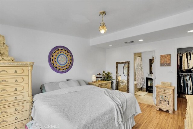 bedroom featuring ensuite bathroom, a closet, light wood-type flooring, visible vents, and recessed lighting