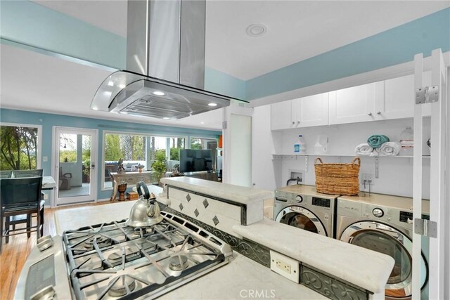 kitchen with white cabinets, recessed lighting, island range hood, washing machine and clothes dryer, and open floor plan