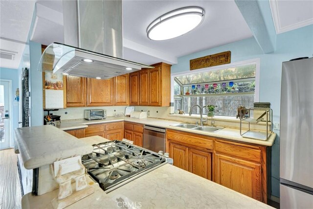 kitchen featuring island exhaust hood, a sink, a toaster, light countertops, and appliances with stainless steel finishes