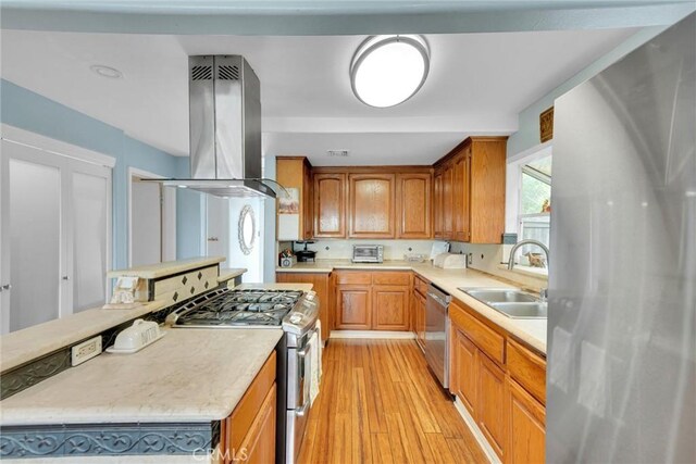 kitchen featuring light countertops, appliances with stainless steel finishes, island range hood, and a sink