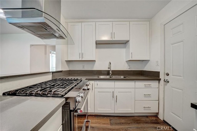 kitchen featuring dark wood finished floors, stainless steel range with gas cooktop, white cabinetry, a sink, and extractor fan