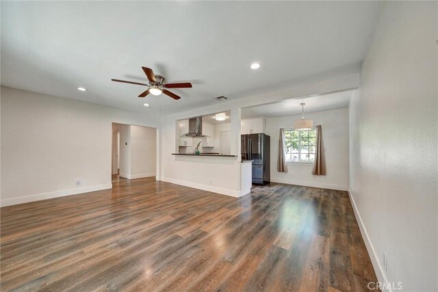 unfurnished living room with dark wood-style floors, baseboards, and a ceiling fan