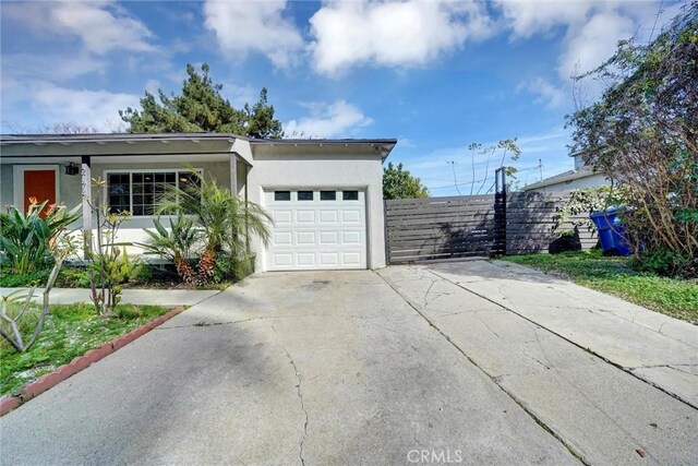 view of side of property with fence, stucco siding, a garage, and concrete driveway
