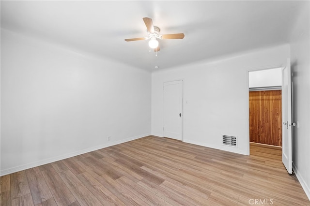 empty room with light wood finished floors, baseboards, visible vents, and a ceiling fan