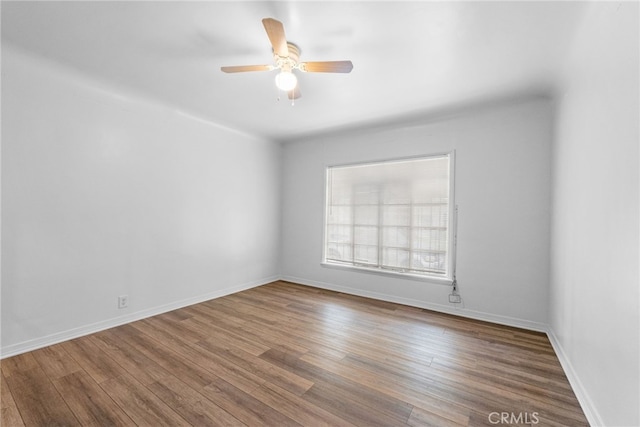 unfurnished room featuring baseboards, wood finished floors, and ceiling fan