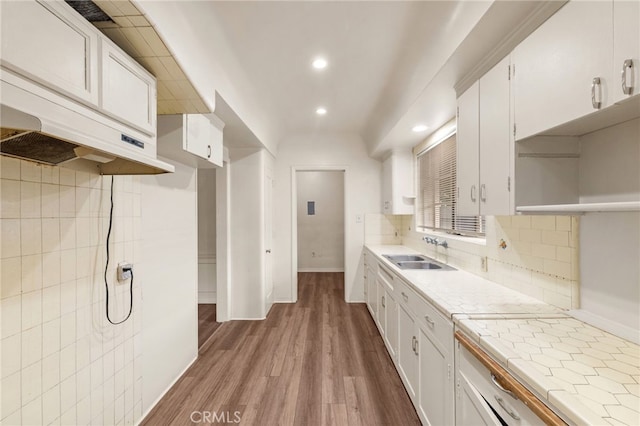 kitchen featuring wood finished floors, recessed lighting, tasteful backsplash, white cabinetry, and a sink