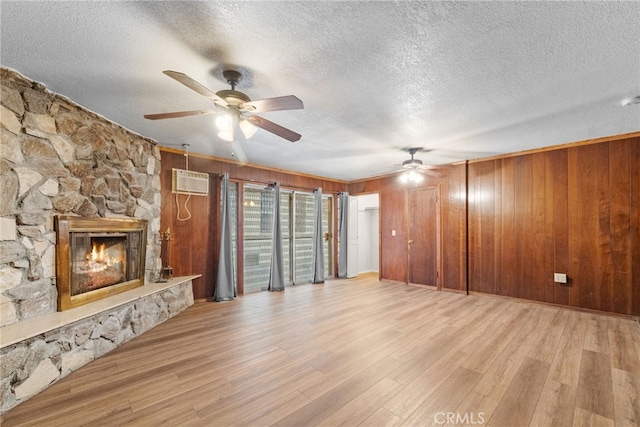 unfurnished living room with wood finished floors, wooden walls, a wall mounted air conditioner, and ceiling fan