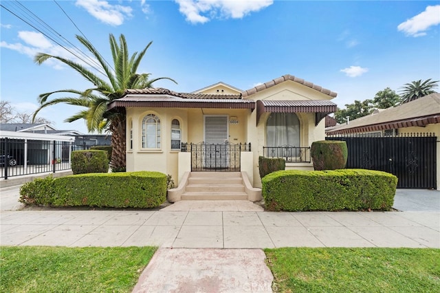 view of front of home with stucco siding, a tile roof, fence, and covered porch