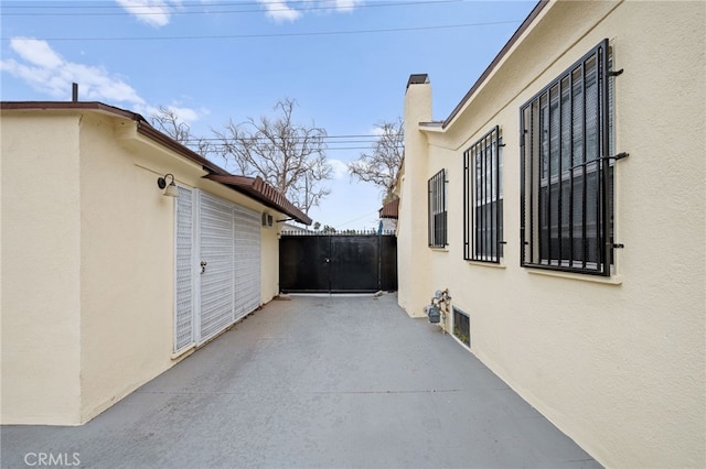 view of side of property featuring a chimney, stucco siding, and a patio area