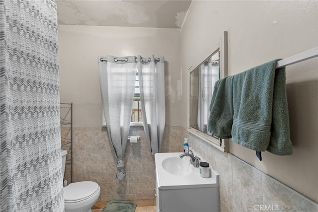 bathroom featuring toilet, vanity, tile patterned flooring, and tile walls