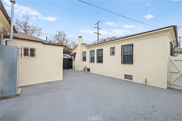 back of house featuring stucco siding, fence, crawl space, a patio area, and a chimney