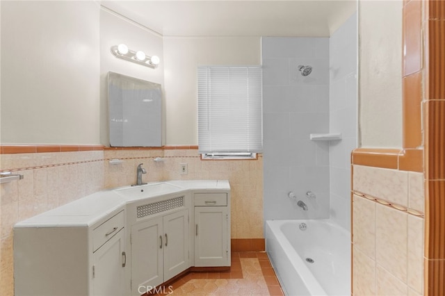 bathroom with tile walls, tile patterned floors, vanity,  shower combination, and wainscoting