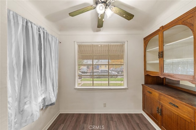 empty room featuring baseboards, ceiling fan, and dark wood-type flooring
