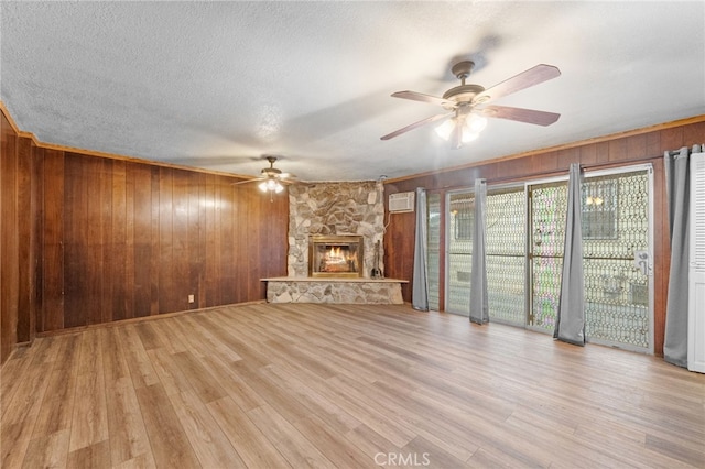 unfurnished living room featuring a ceiling fan, a wall unit AC, wood walls, and wood finished floors