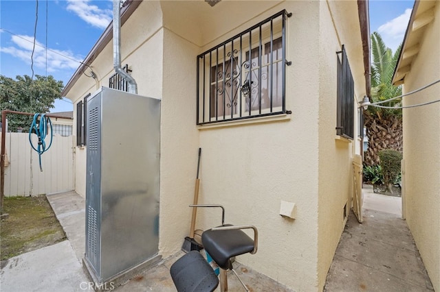 view of home's exterior with stucco siding and fence