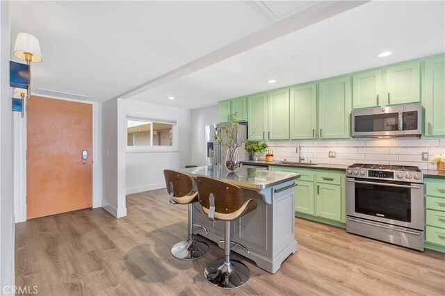 1 3rd Pl Unit 302, Long Beach, CA 90802 - kitchen with appliances with stainless steel finishes, green cabinets, a sink, a kitchen breakfast bar, and decorative backsplash