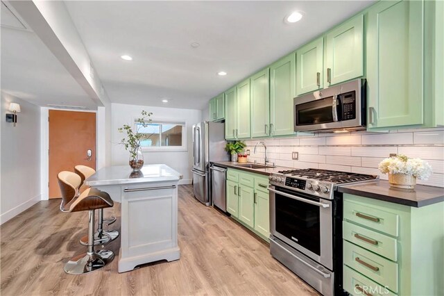 1 3rd Pl Unit 302, Long Beach, CA 90802 - kitchen featuring green cabinetry, appliances with stainless steel finishes, a breakfast bar, backsplash, and a center island