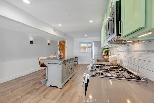 1 3rd Pl Unit 302, Long Beach, CA 90802 - kitchen featuring decorative backsplash, baseboards, a kitchen breakfast bar, appliances with stainless steel finishes, and a center island