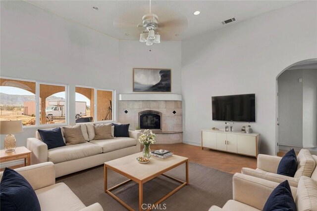 23073 Cielito Dr, Apple Valley, CA 92308 - living room with ceiling fan, arched walkways, a tile fireplace, a towering ceiling, and wood finished floors