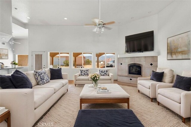 23073 Cielito Dr, Apple Valley, CA 92308 - living room featuring ceiling fan, recessed lighting, a tile fireplace, light wood-style flooring, and a high ceiling