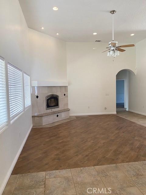 23073 Cielito Dr, Apple Valley, CA 92308 - unfurnished living room with ceiling fan, a tiled fireplace, arched walkways, and recessed lighting