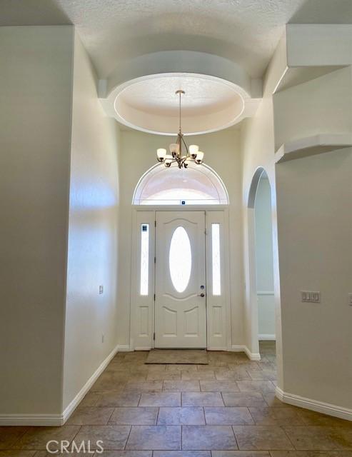 23073 Cielito Dr, Apple Valley, CA 92308 - entrance foyer with arched walkways, a chandelier, a high ceiling, and stone finish flooring