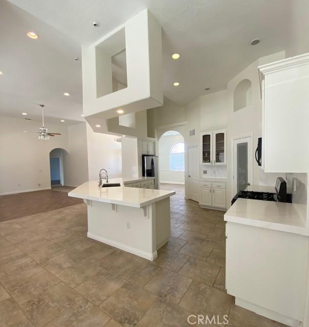 23073 Cielito Dr, Apple Valley, CA 92308 - kitchen featuring arched walkways, stainless steel fridge with ice dispenser, a ceiling fan, white cabinetry, and a high ceiling