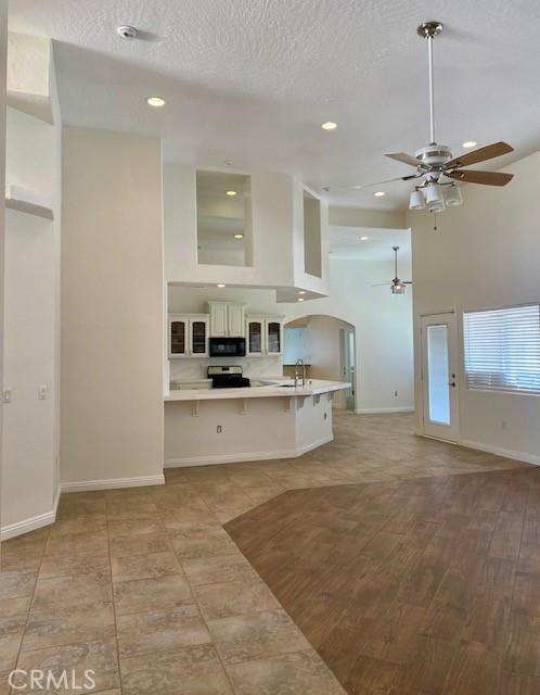 23073 Cielito Dr, Apple Valley, CA 92308 - kitchen featuring a ceiling fan, a breakfast bar area, a peninsula, light countertops, and glass insert cabinets