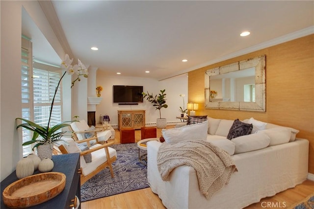 living area featuring a fireplace, wood finished floors, recessed lighting, and crown molding