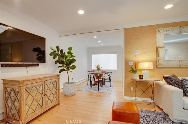 living area with crown molding, a baseboard heating unit, baseboards, recessed lighting, and wood finished floors