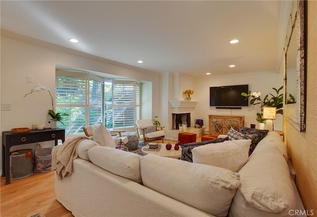 living area featuring a fireplace, light wood-style flooring, recessed lighting, and ornamental molding