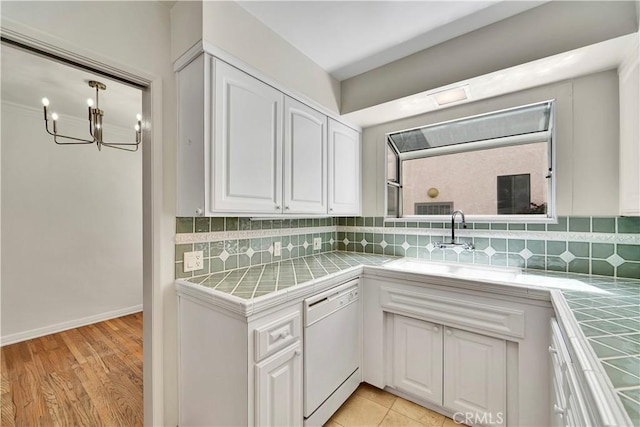 clothes washing area featuring a sink, a notable chandelier, and baseboards