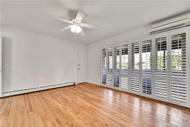 unfurnished room with wood finished floors, a baseboard radiator, ceiling fan, a wall mounted AC, and baseboards