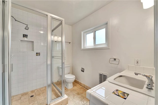 bathroom featuring a shower stall, a sink, visible vents, baseboards, and toilet